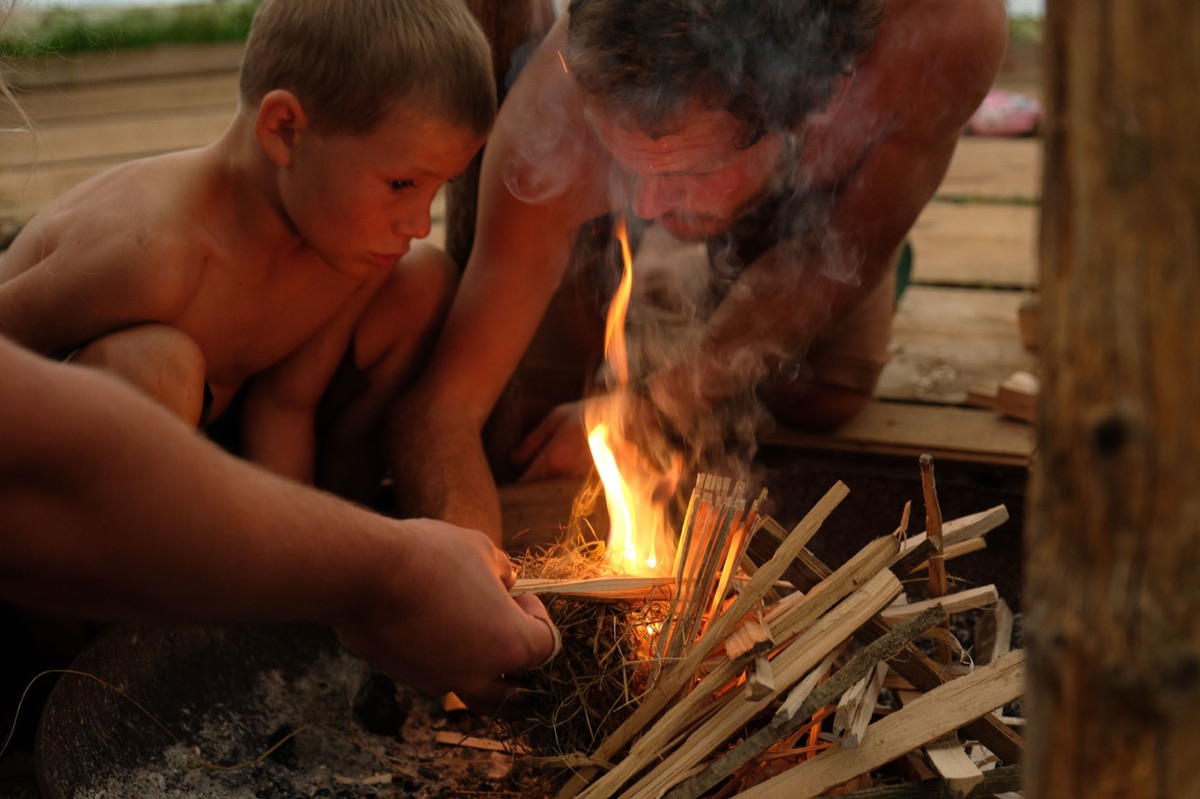 Erwachsener und Kind entfachen gemeinsam ein Feuer